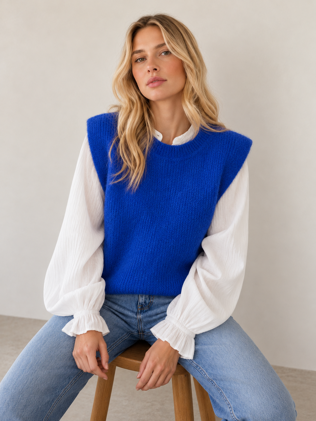 Alpaka Pullunder Alma in Blau am Model mit weißer Bluse und Jeans